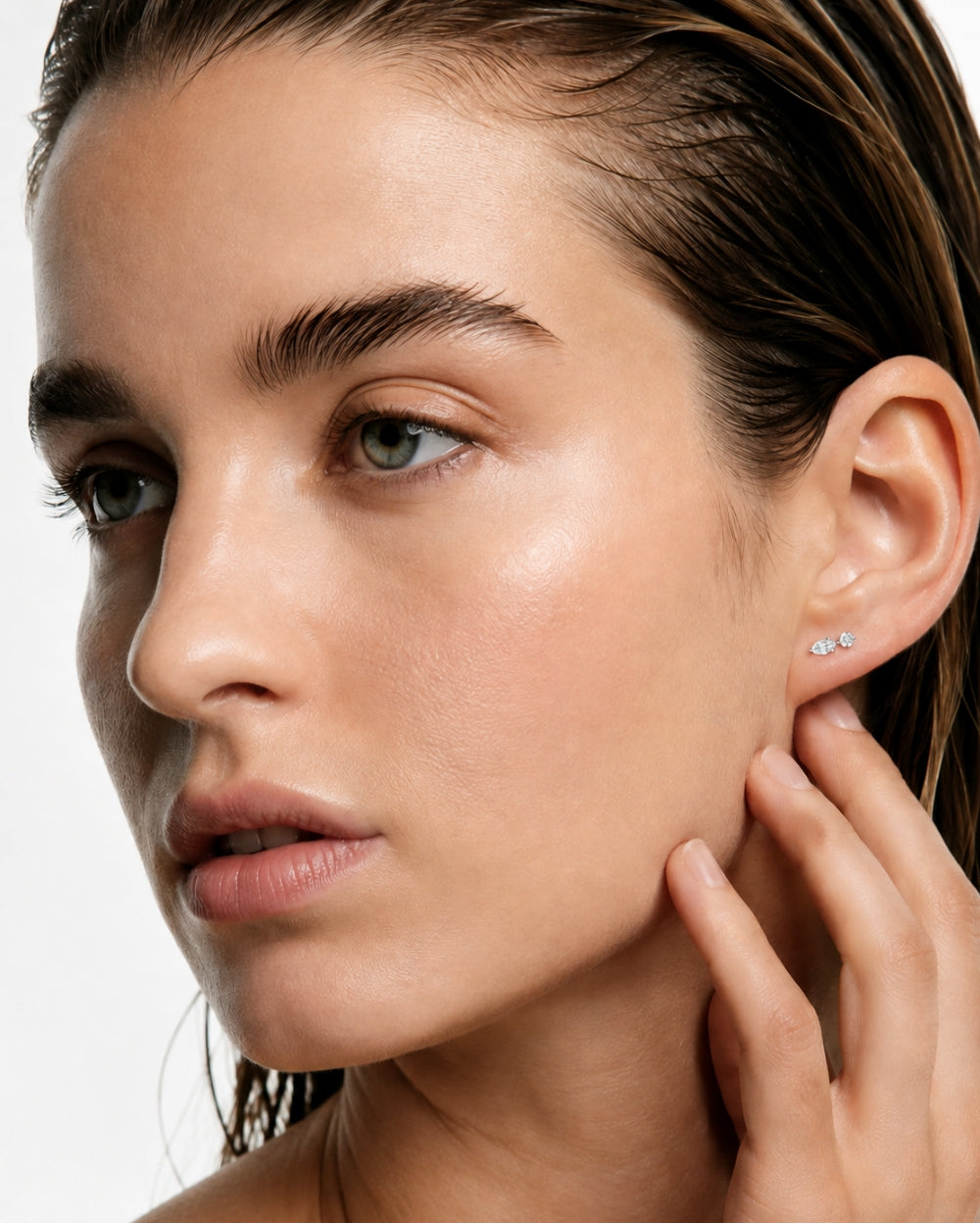 Model wearing marquise and round diamond earring on white background.
