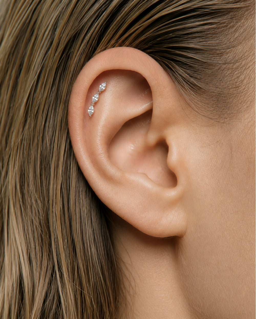 Close up of ear with Marquise Diamond Trilogy Earring set in white gold in Helix position.
