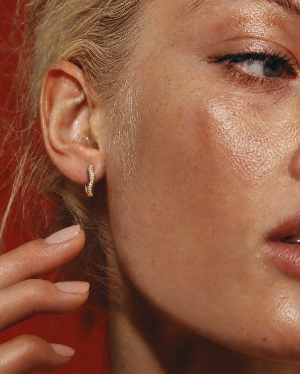 Gold and Diamond wave hoop earring in models ear.